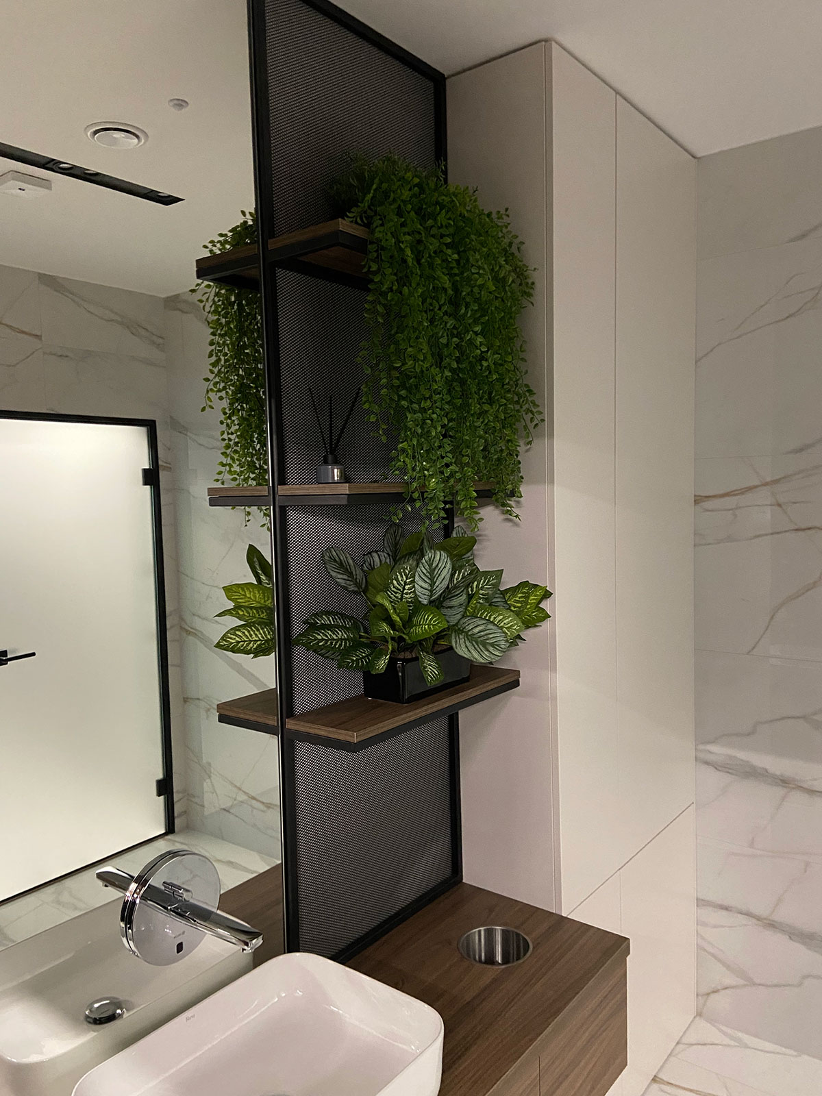 Łazienka z umywalką, lustrem i rośliną.