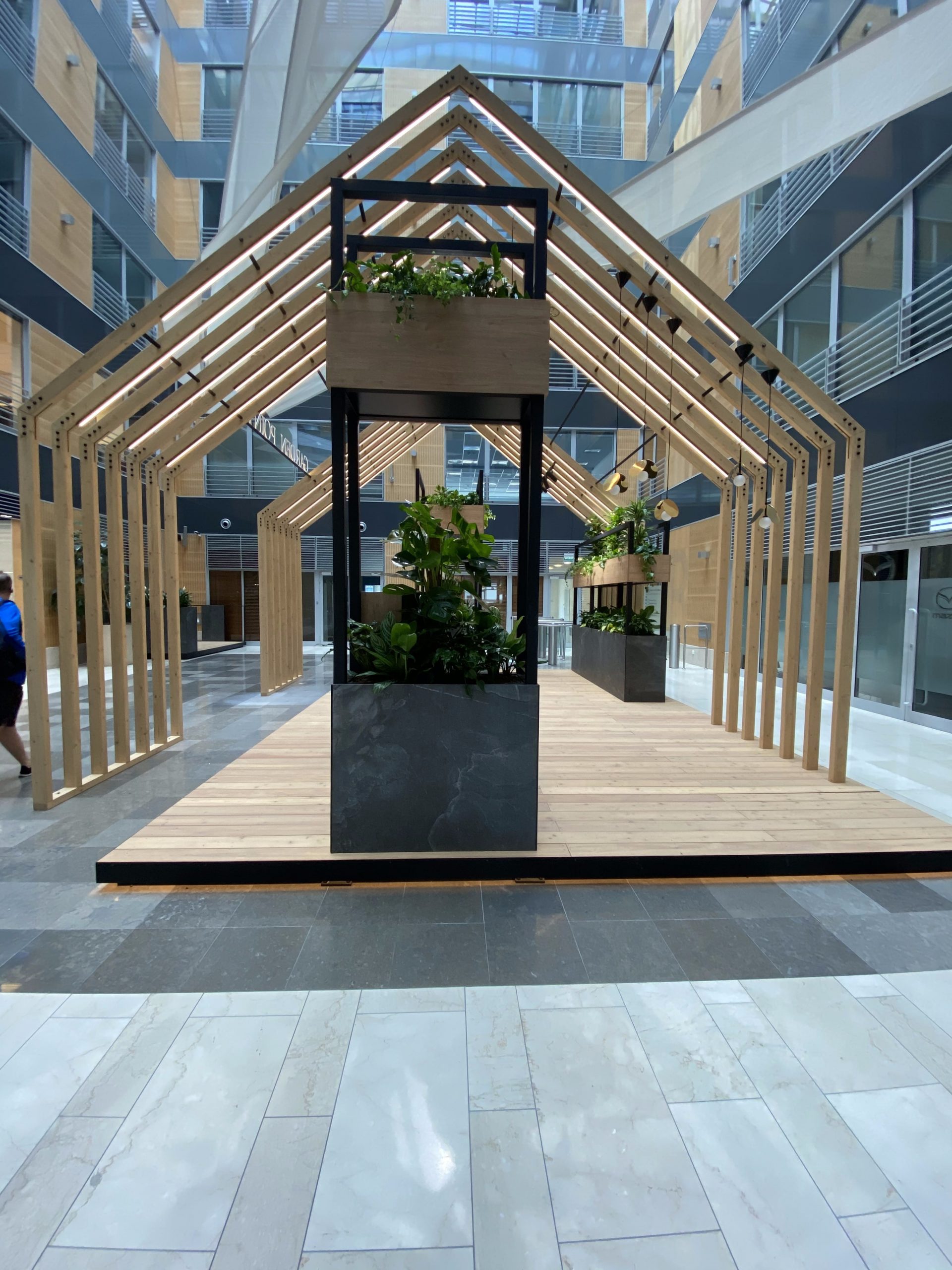 Drewniana konstrukcja z roślinami w budynku biurowym.