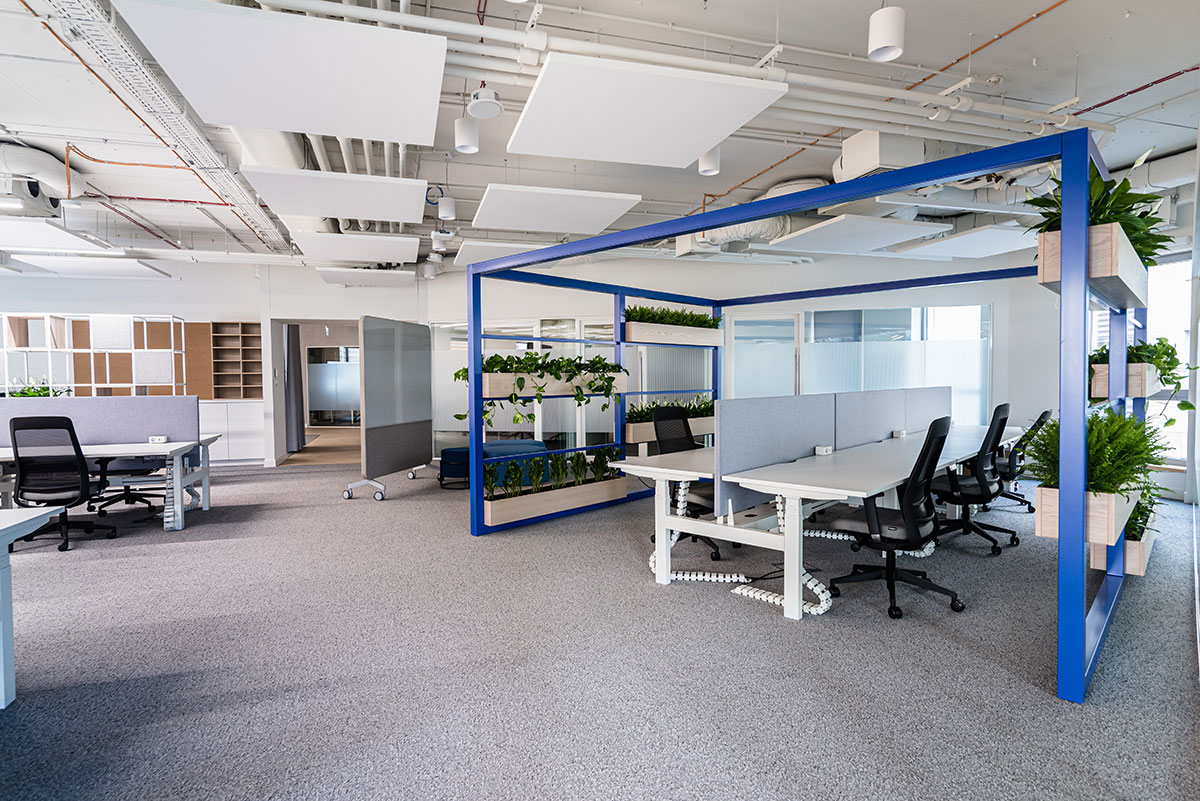 Niebiesko-białe biuro z roślinami i biurkami.