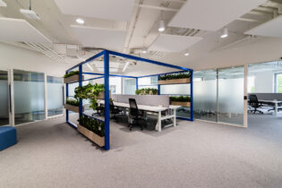 Nowoczesne biuro z roślinami i szklaną ścianą.