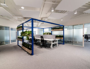 Nowoczesne biuro z roślinami i szklaną ścianą.