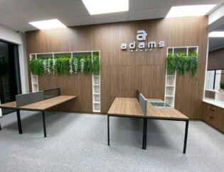 Nowoczesne biuro z drewnianym biurkiem i roślinami na ścianie.