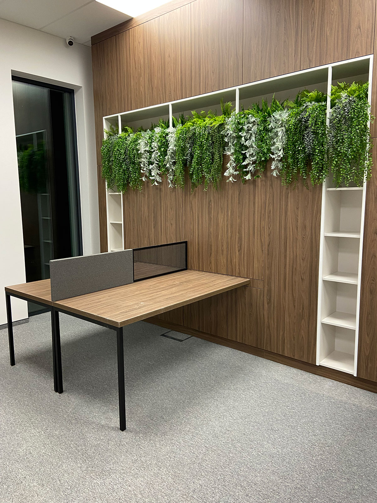 Biuro z biurkiem i roślinami na ścianie.