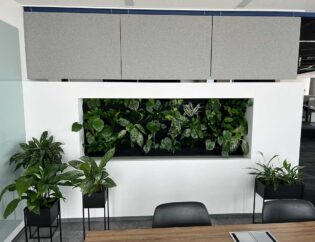 Biuro w stylu Booksy ze ścianą roślin i biurkiem.