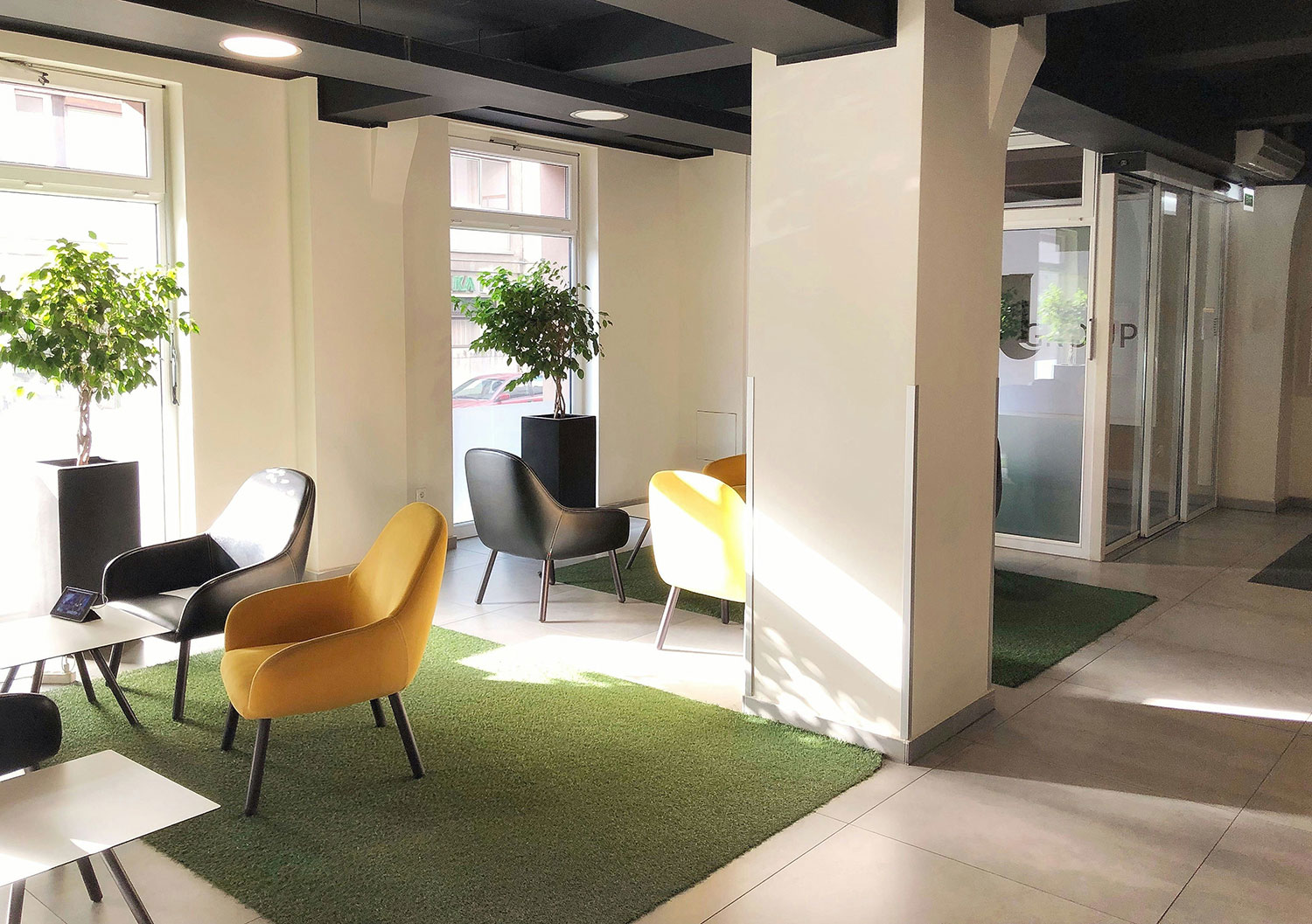 Nowoczesny salon biurowy z żółtymi i czarnymi krzesłami, małymi stolikami, roślinami doniczkowymi i dużymi oknami zapewniającymi naturalne światło. Wnętrze urządzono zgodnie z normami WELL i LEED, tworząc zdrowsze miejsce pracy. Nowoczesny salon biurowy z żółtymi i czarnymi krzesłami, małymi stolikami, roślinami doniczkowymi i dużymi oknami zapewniającymi naturalne światło. Wnętrze urządzono zgodnie z normami WELL i LEED, tworząc zdrowsze miejsce pracy.